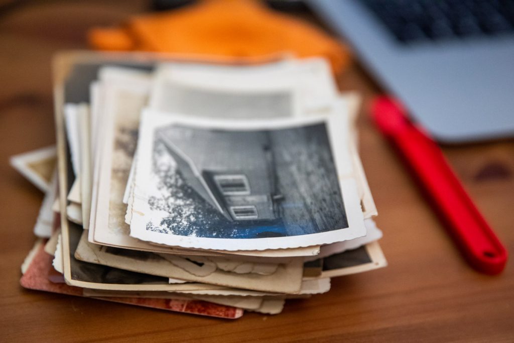 A stack of old black and white photographs sits on a person's desk.