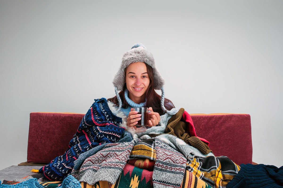 A woman wears multiple layers of clothes in her home. 