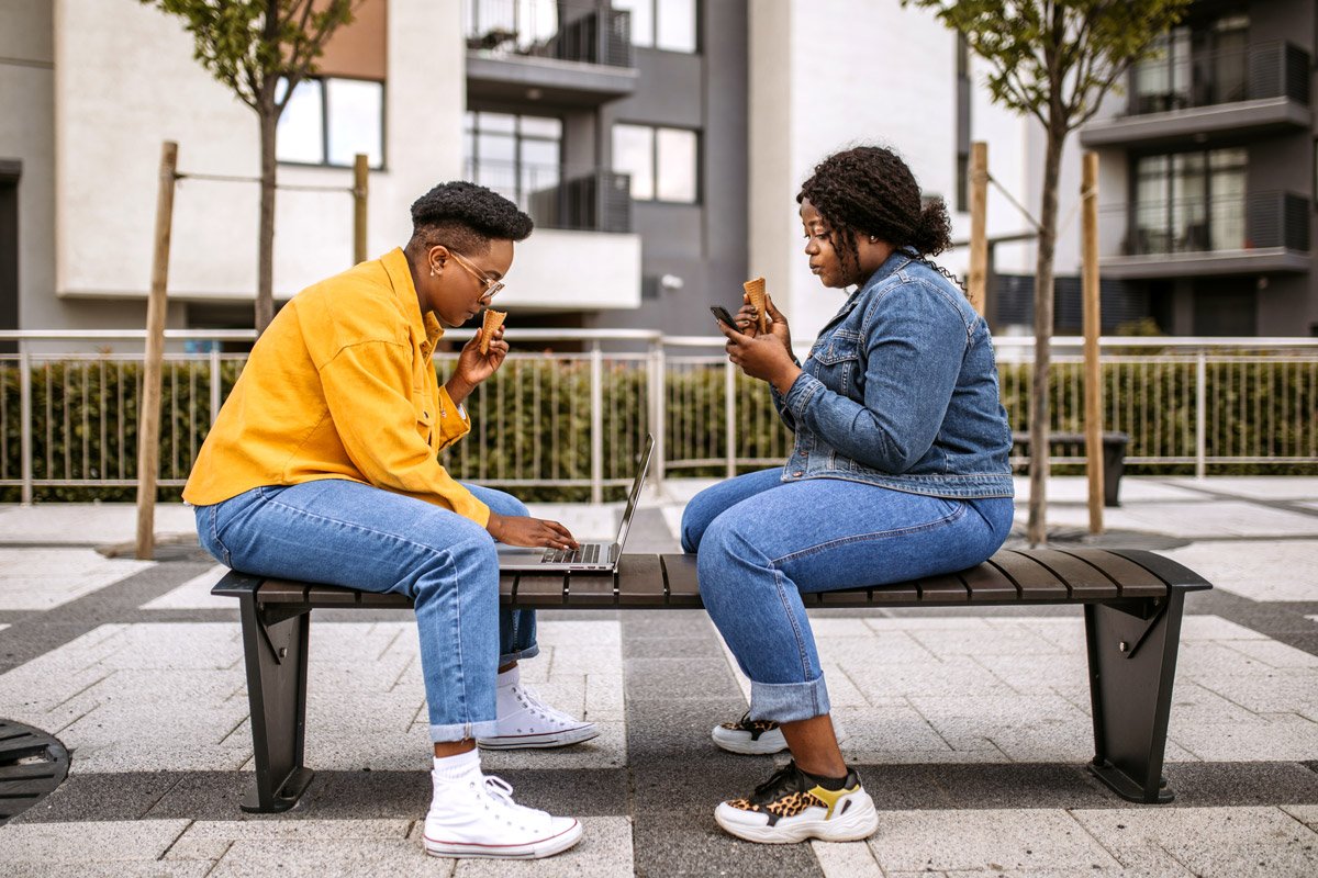 Two women eat ice cream as they study for an exam.