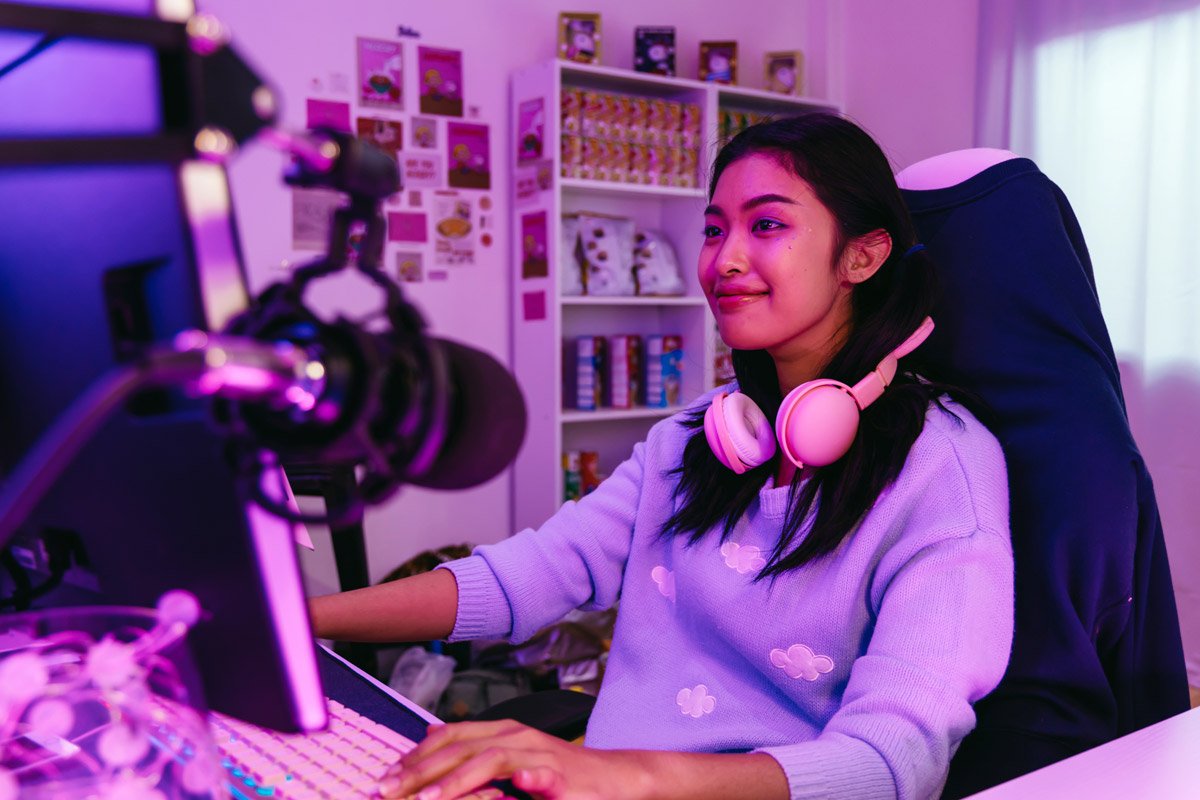 A woman plays an online game on her computer in her bedroom.