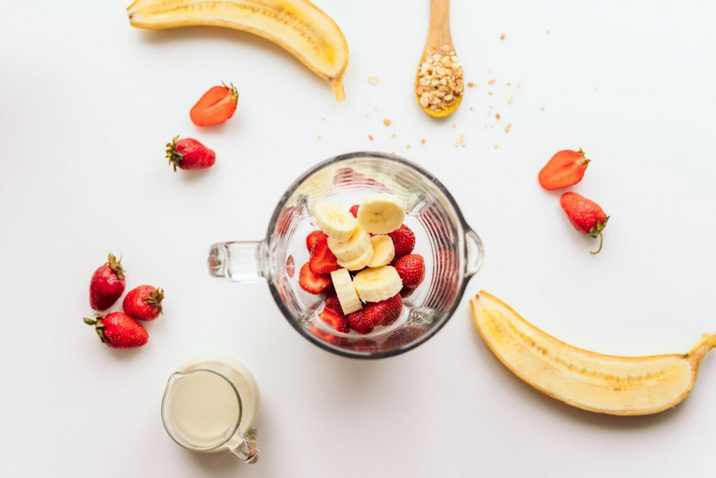 Bananas and strawberries sit in a blender.