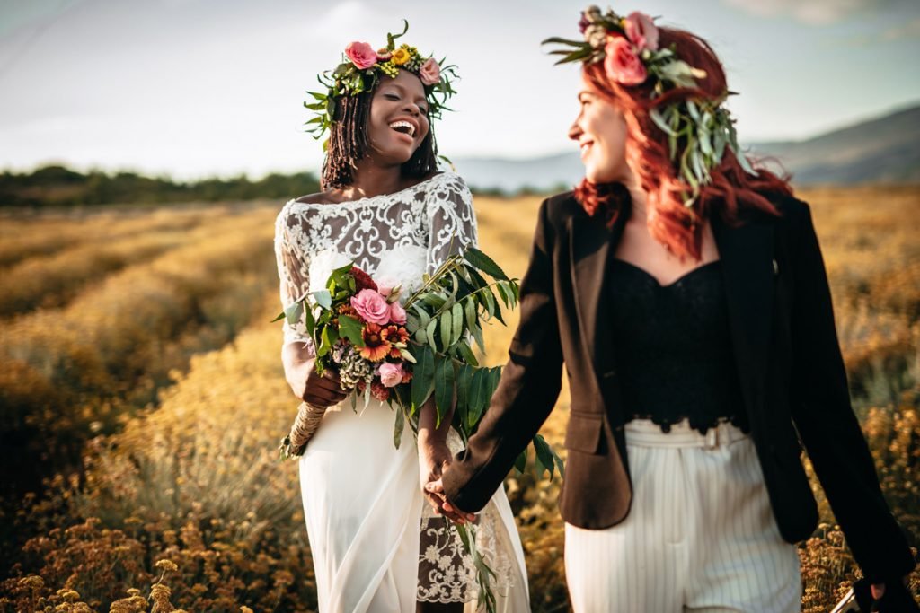 Two women who were just married to each other walk in a field for their wedding portraits.