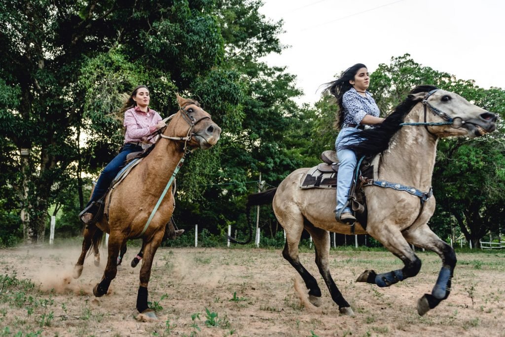 Two women ride horses. 