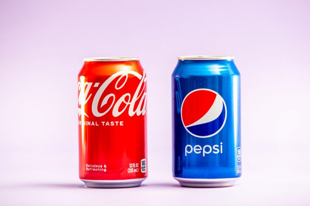 A can of Coke and Pepsi stand next to each other.
