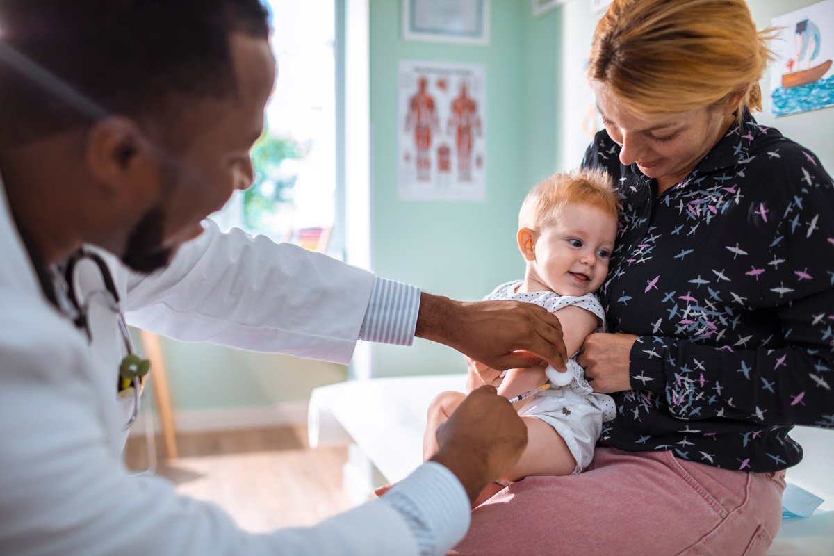 A mother holds her baby as he gets his shots at the doctor's office.