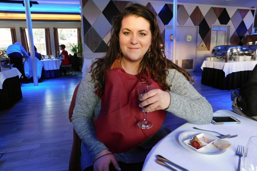 A woman holds a drink while sitting at a table at a corporate event. 