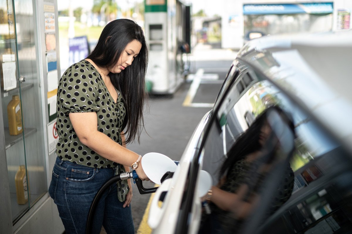 A woman fills her tank up with gas.