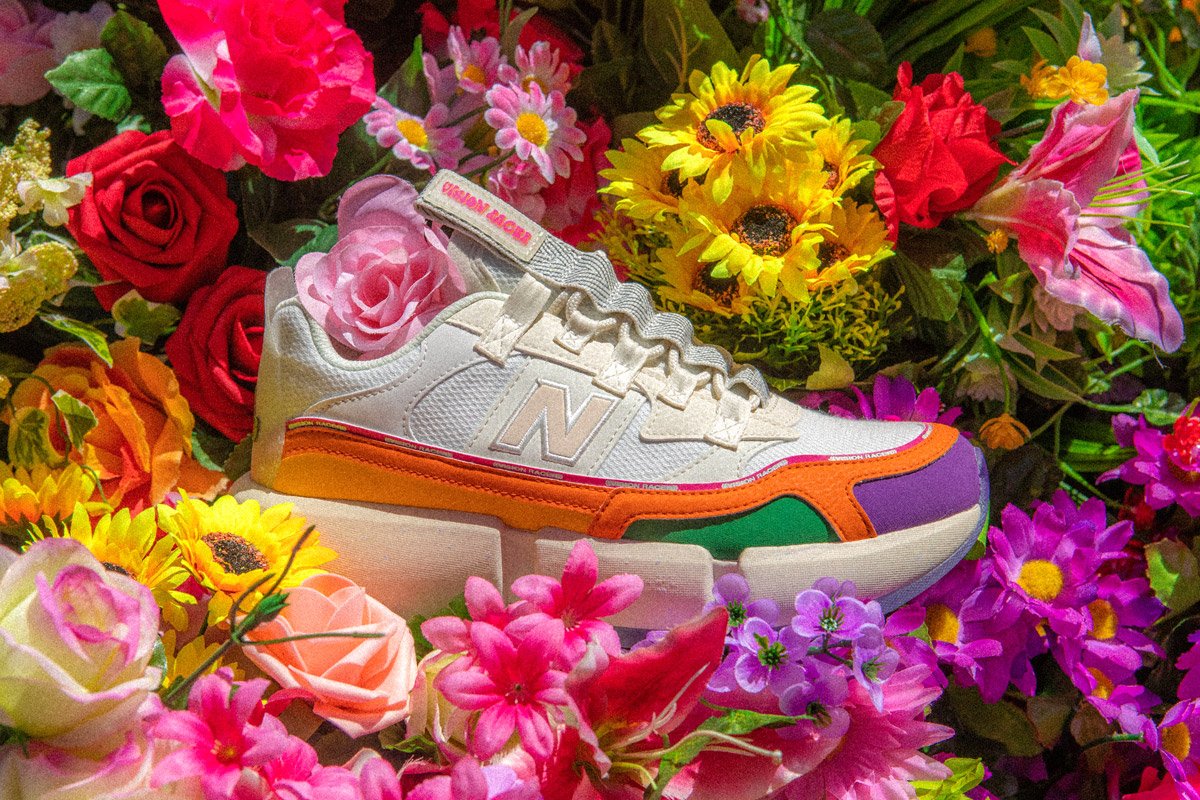 A new balance sneaker lays in a bed of flowers. 