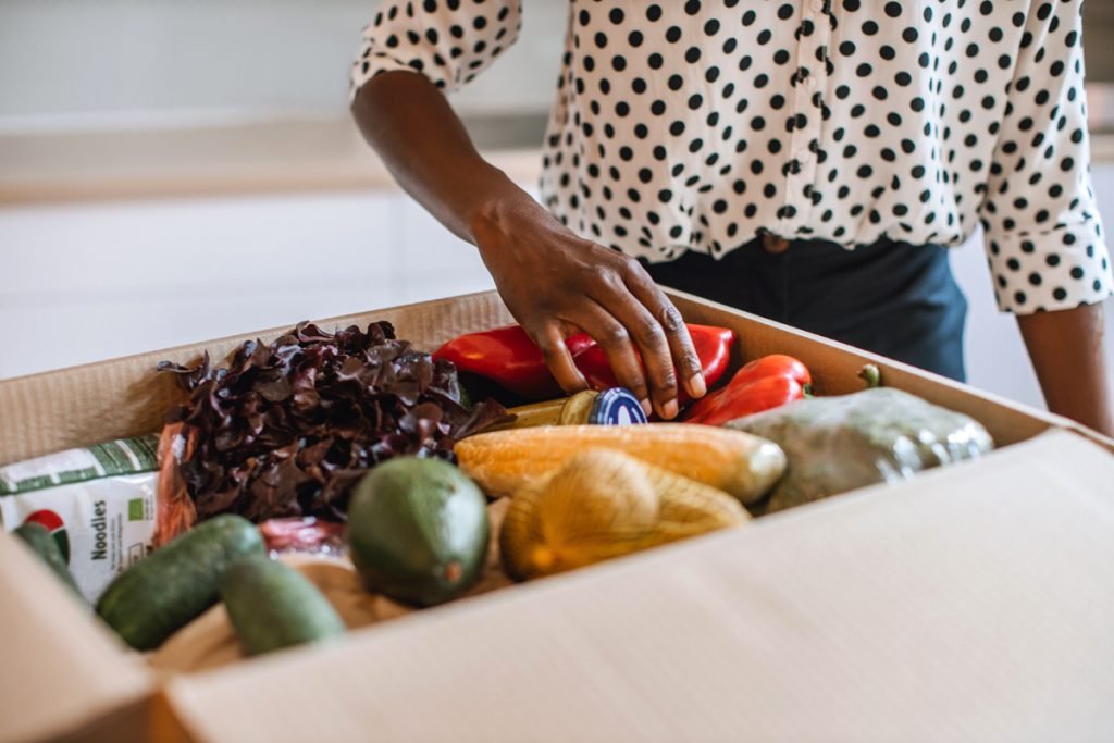 A woman opens up a meal kit delivery box.