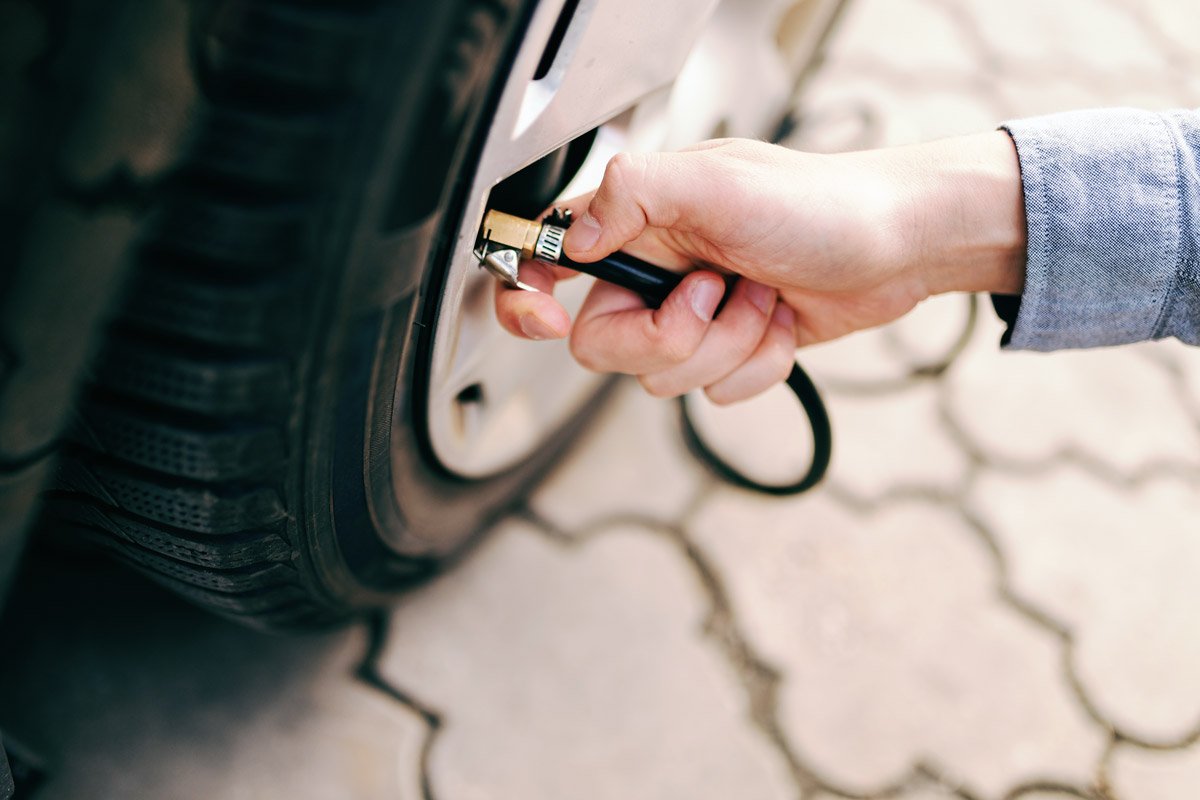 A person checks there tire pressure.