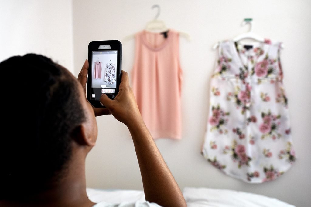 A woman uses her cell phone to photograph clothes she is selling online.