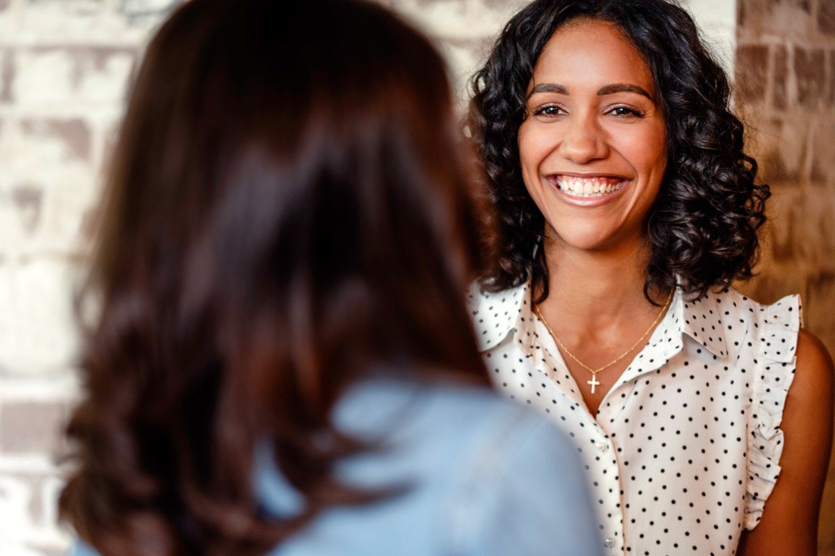 A woman smiles as she talks to her boss at her office job.