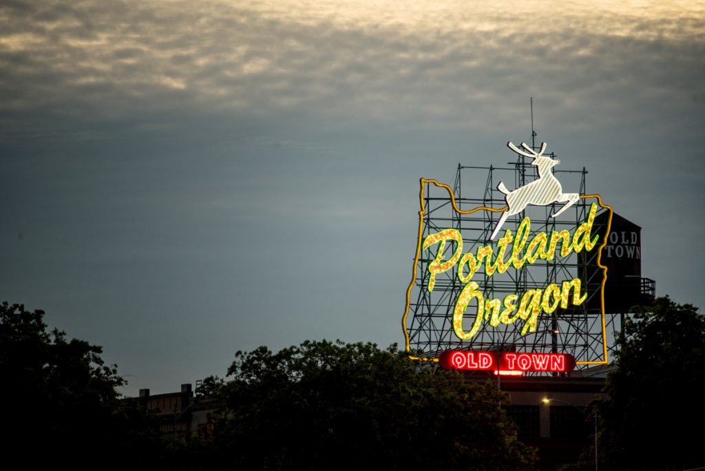 A portland, oregon sign is is shown in the skyline at dusk.